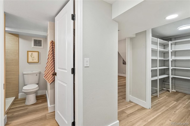 bathroom with toilet, wood finished floors, and baseboards