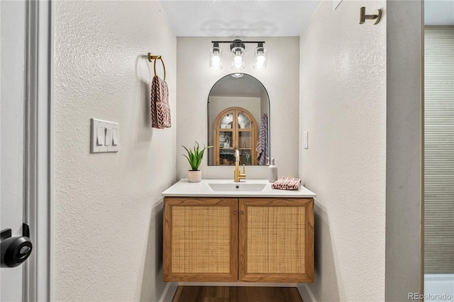 bathroom featuring vanity, wood finished floors, and a textured wall