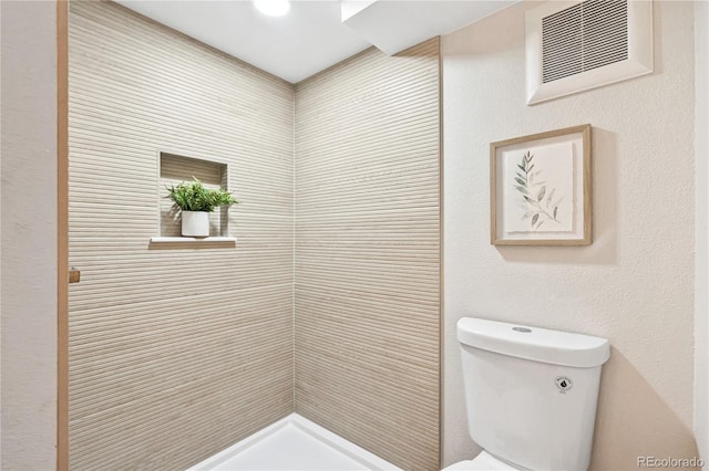 full bath with toilet, visible vents, and tiled shower