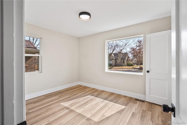 spare room with a wealth of natural light, visible vents, and wood finished floors