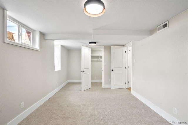 below grade area featuring visible vents, carpet flooring, and baseboards