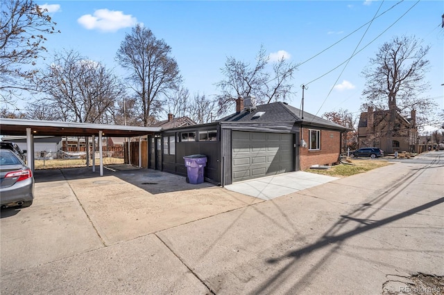 exterior space with brick siding, an attached garage, concrete driveway, and a carport