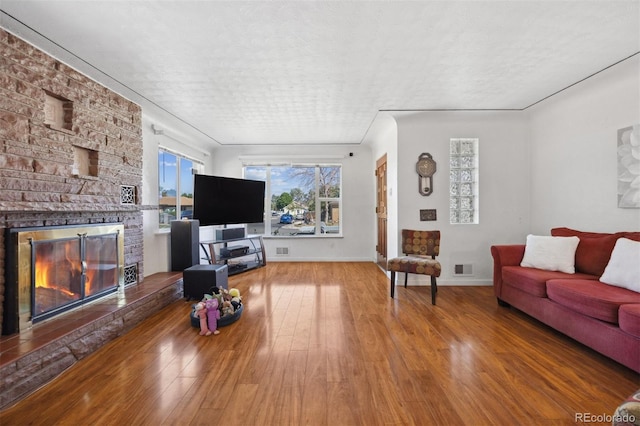 living room featuring a textured ceiling, a large fireplace, and hardwood / wood-style floors