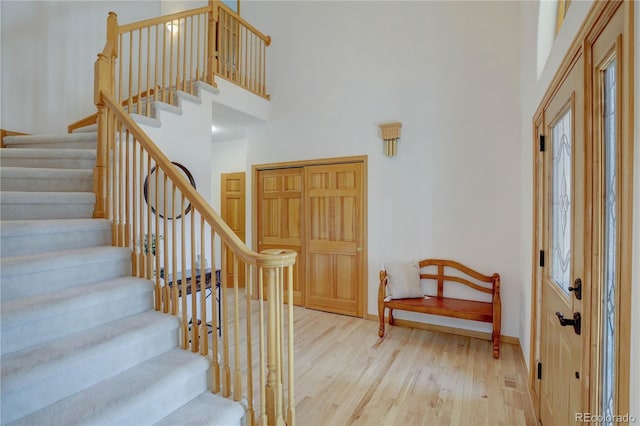 entrance foyer featuring wood finished floors, a towering ceiling, stairs, and baseboards