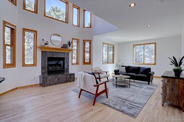 living area featuring a tiled fireplace, wood finished floors, baseboards, and recessed lighting