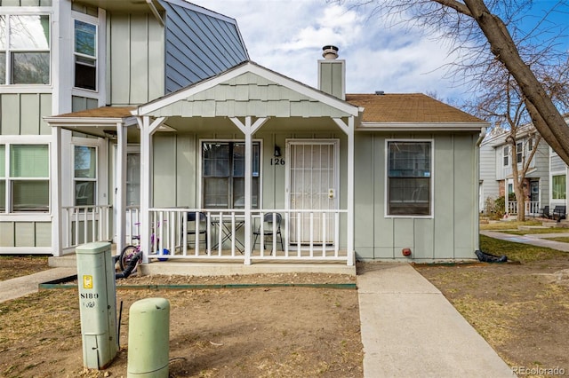 view of front of house with a porch, a chimney, board and batten siding, and a shingled roof