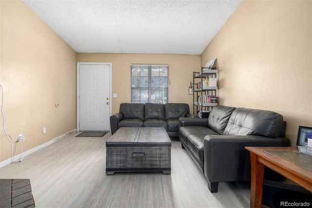 living room featuring light wood-style flooring, baseboards, and a textured ceiling