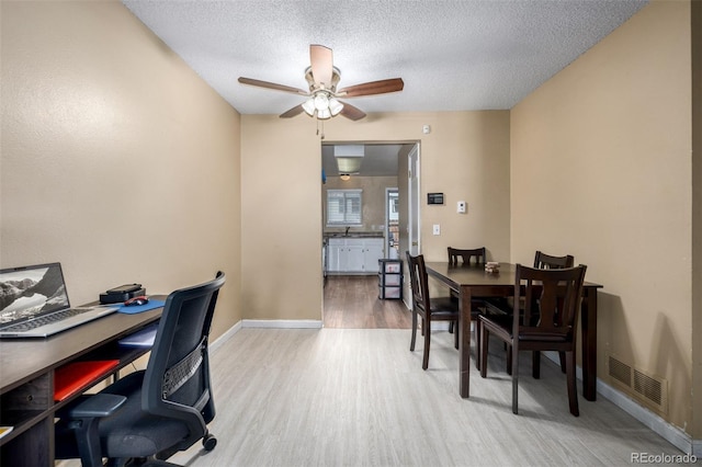 office featuring wood finished floors, baseboards, a ceiling fan, visible vents, and a textured ceiling