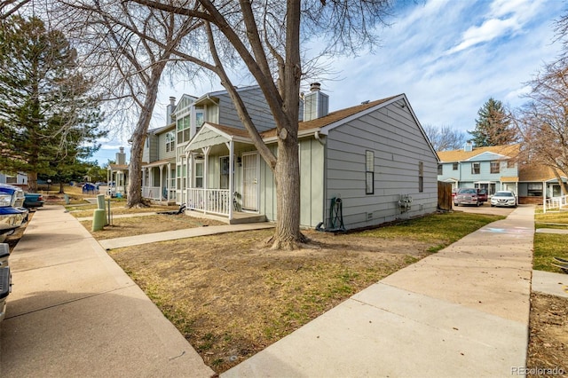 view of property exterior featuring a porch, a residential view, and a chimney