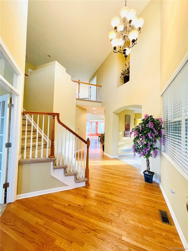 16866 E Peakview Ave, Aurora, CO 80016 - entryway featuring wood finished floors, a chandelier, stairs, a towering ceiling, and arched walkways