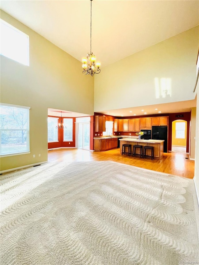 16866 E Peakview Ave, Aurora, CO 80016 - unfurnished living room featuring a high ceiling, a chandelier, light wood-type flooring, and plenty of natural light