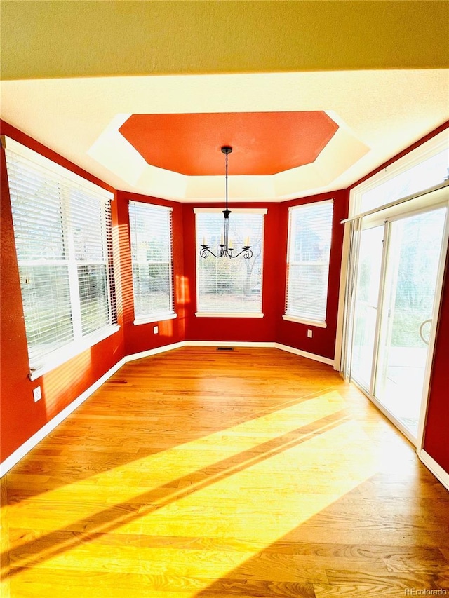 16866 E Peakview Ave, Aurora, CO 80016 - unfurnished dining area with a tray ceiling, light wood-style floors, a chandelier, and healthy amount of natural light