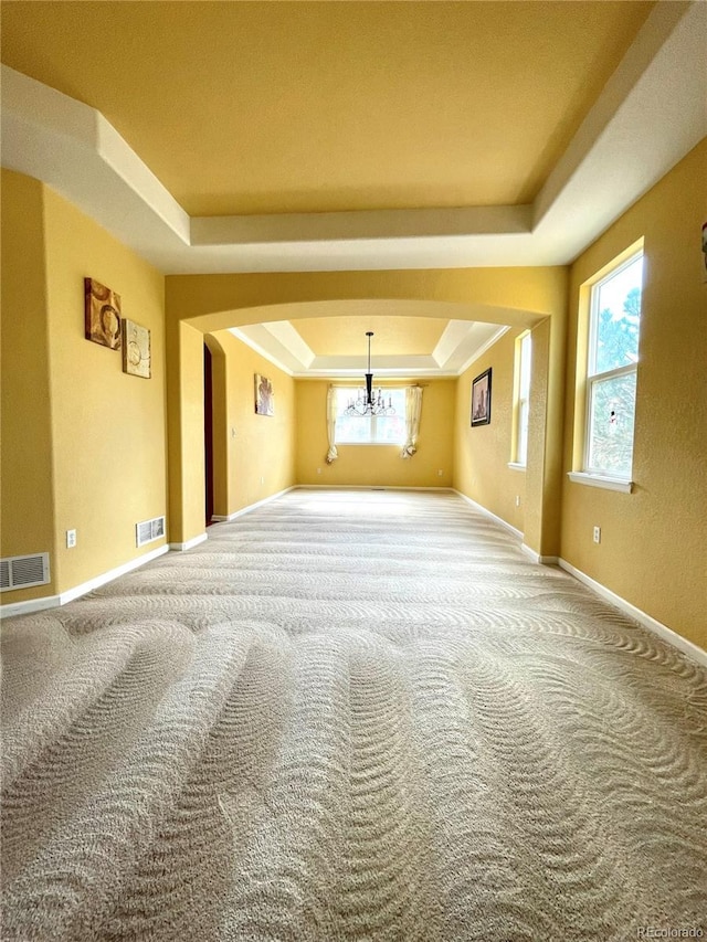 16866 E Peakview Ave, Aurora, CO 80016 - carpeted empty room with a tray ceiling, arched walkways, and a chandelier