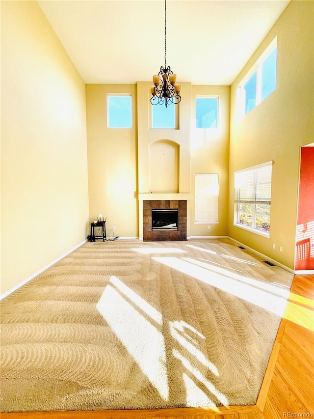 16866 E Peakview Ave, Aurora, CO 80016 - unfurnished living room with a chandelier, a towering ceiling, a fireplace, and wood finished floors