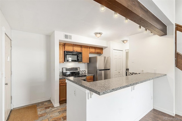 kitchen featuring stainless steel appliances, brown cabinetry, a peninsula, a kitchen bar, and baseboards
