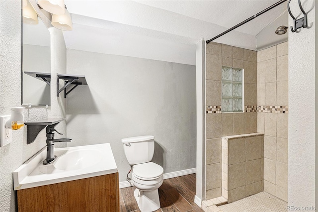 bathroom featuring a walk in shower, wood finished floors, toilet, baseboards, and vanity