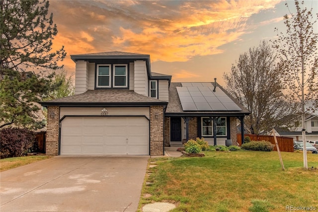view of front of home featuring solar panels, brick siding, a garage, driveway, and a front lawn