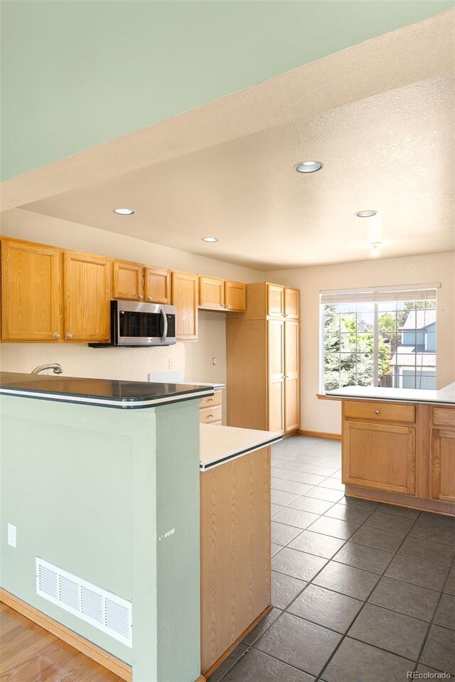 8879 Apache Plume Dr, Parker, CO 80134 - kitchen with stainless steel microwave, recessed lighting, baseboards, tile patterned floors, and light brown cabinets