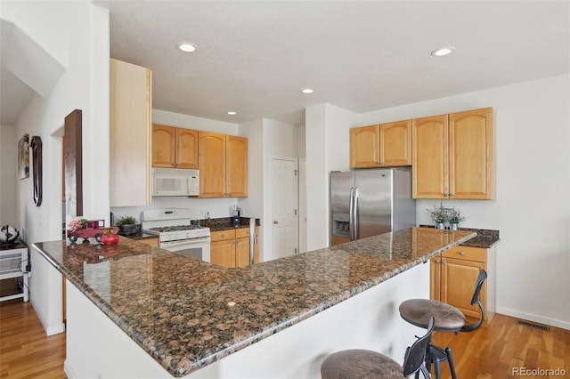 16665 Kenuil St, Brighton, CO 80603 - kitchen with white appliances, light wood-style floors, light brown cabinets, and recessed lighting