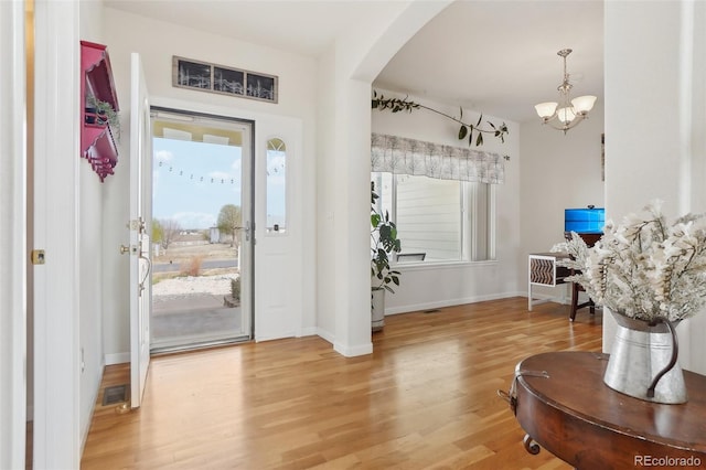 16665 Kenuil St, Brighton, CO 80603 - entryway with light wood-style floors, arched walkways, baseboards, and a chandelier
