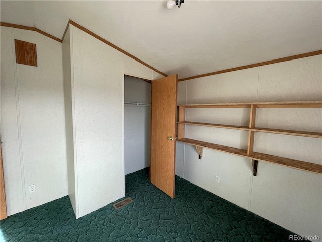 unfurnished bedroom with lofted ceiling, dark carpet, a closet, and ornamental molding