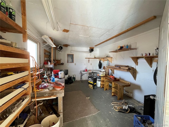 interior space with a workshop area, electric panel, concrete flooring, and a baseboard radiator