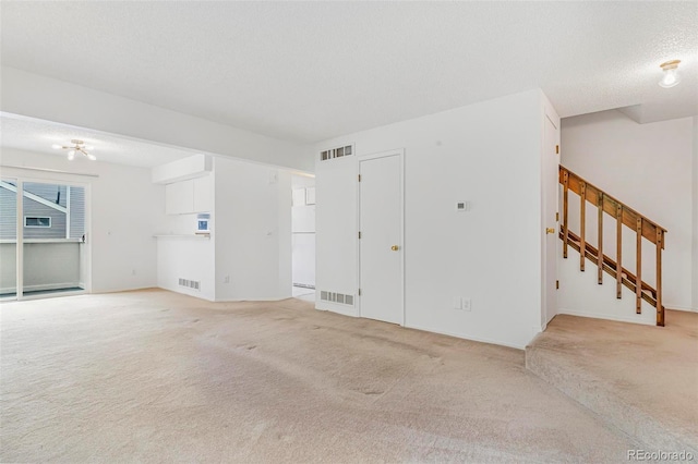 72 S Nome St, Aurora, CO 80012 - unfurnished living room with light carpet, stairs, and a textured ceiling
