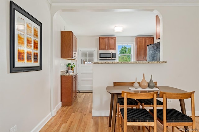 1691 Roslyn St, Denver, CO 80220 - dining space featuring light wood-style flooring, arched walkways, baseboards, and crown molding