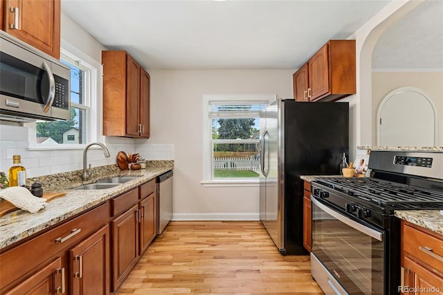 1691 Roslyn St, Denver, CO 80220 - kitchen with stainless steel appliances, a sink, light wood finished floors, light stone counters, and decorative backsplash
