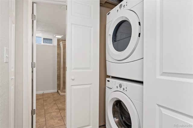 1691 Roslyn St, Denver, CO 80220 - laundry room featuring stacked washer and clothes dryer, light tile patterned flooring, and baseboards