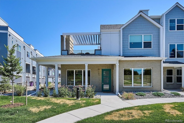 888 S Valentia St Unit 20-101, Denver, CO 80247 - view of front facade featuring brick siding, a balcony, a front lawn, and covered porch