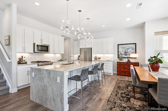 888 S Valentia St Unit 20-101, Denver, CO 80247 - kitchen featuring appliances with stainless steel finishes, a chandelier, light wood-style flooring, backsplash, and white cabinets