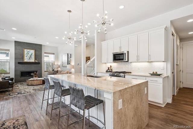 888 S Valentia St Unit 20-101, Denver, CO 80247 - kitchen featuring stainless steel microwave, open floor plan, recessed lighting, stove, and healthy amount of natural light