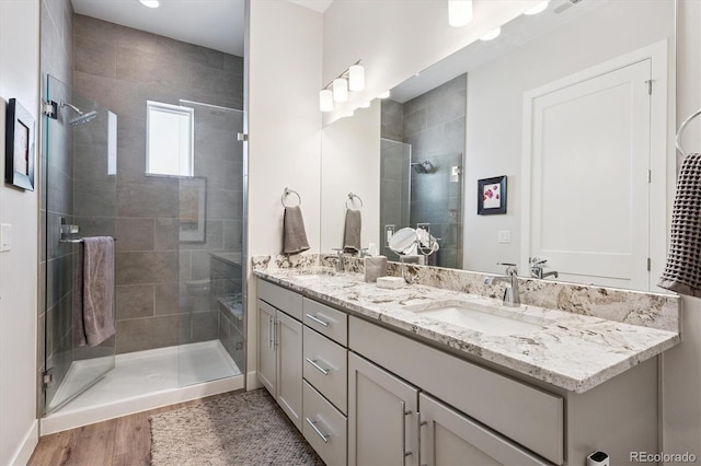 888 S Valentia St Unit 20-101, Denver, CO 80247 - bathroom featuring double vanity, a shower stall, and wood finished floors