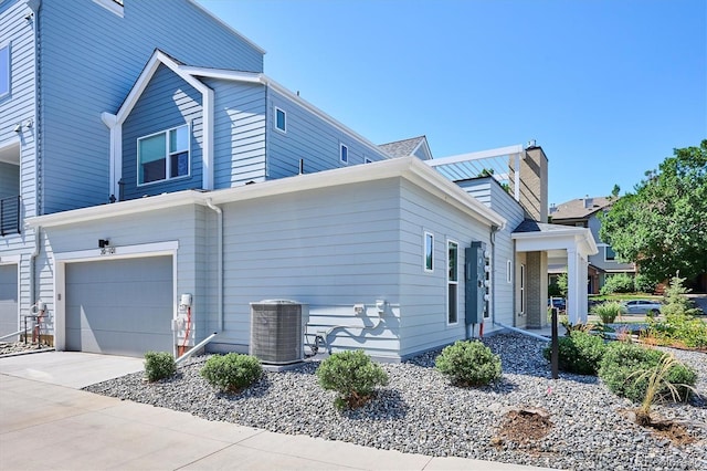 888 S Valentia St Unit 20-101, Denver, CO 80247 - view of side of property featuring a garage, driveway, and a chimney