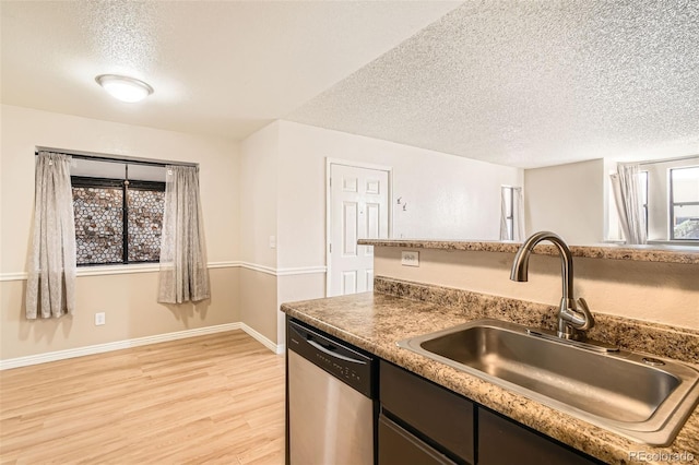 kitchen featuring a sink, stainless steel dishwasher, a textured ceiling, and light wood finished floors