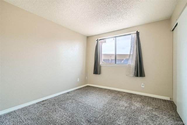 spare room featuring carpet flooring, a textured ceiling, and baseboards