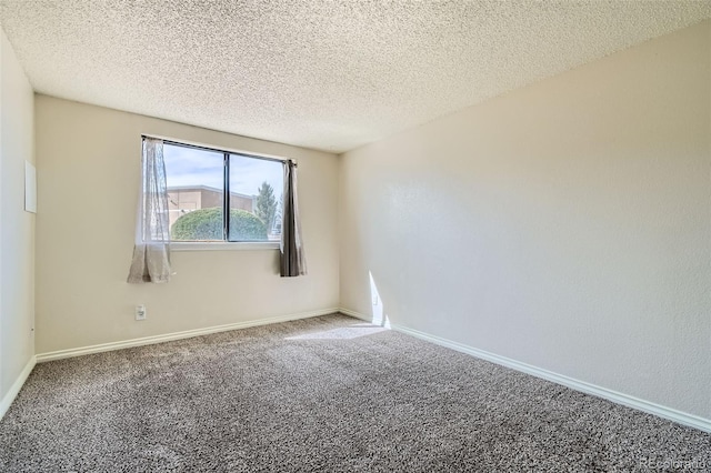 carpeted spare room featuring baseboards and a textured ceiling