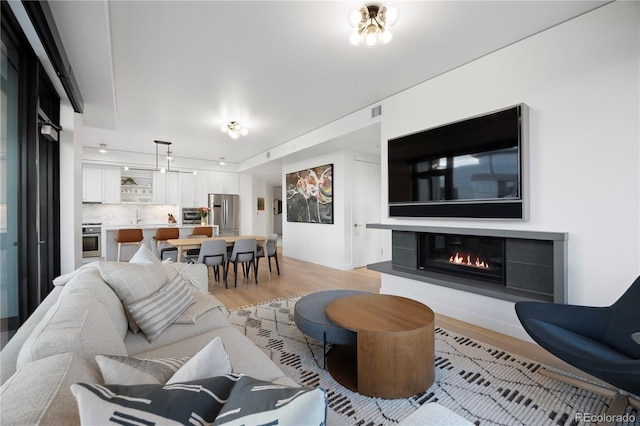 1750 Wewatta St Unit 1720, Denver, CO 80202 - living area with light wood-style floors, a glass covered fireplace, and baseboards
