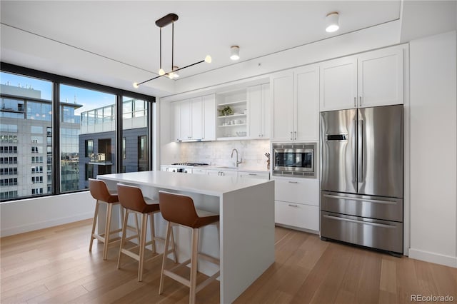 1750 Wewatta St Unit 1720, Denver, CO 80202 - kitchen with stainless steel appliances, open shelves, a center island, light wood finished floors, and a sink