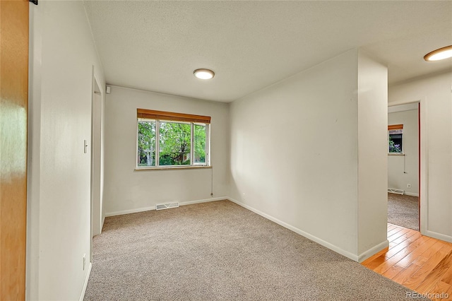 spare room featuring baseboards, carpet, and wood finished floors