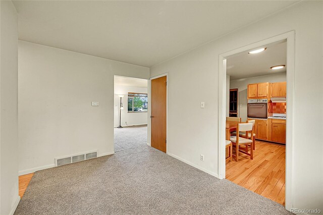 empty room featuring baseboards and light carpet