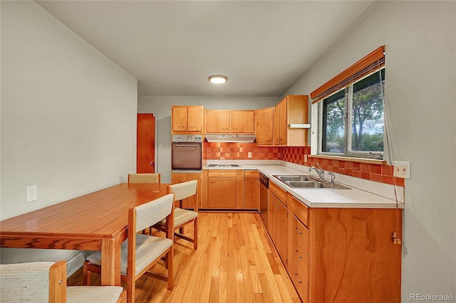 kitchen featuring oven, under cabinet range hood, white cooktop, backsplash, and light countertops