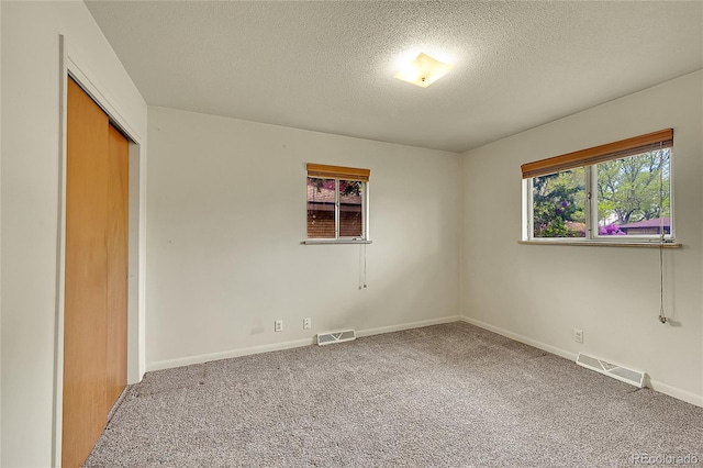 unfurnished bedroom featuring a textured ceiling, carpet flooring, a closet, and baseboards