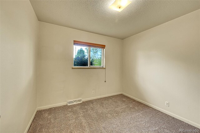 carpeted spare room featuring baseboards and a textured ceiling
