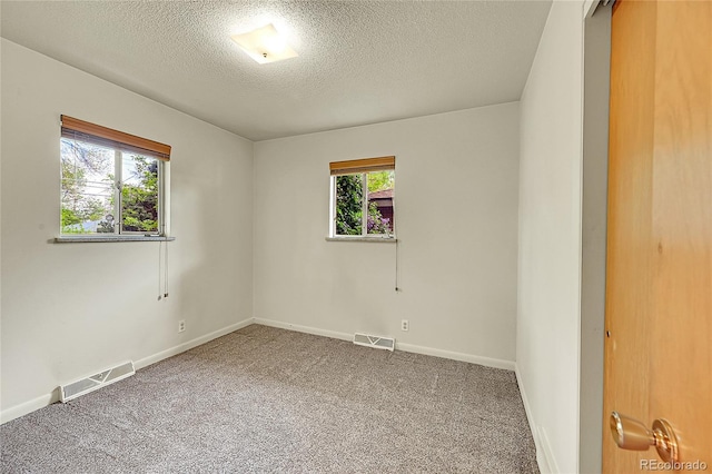 carpeted spare room featuring a textured ceiling and baseboards