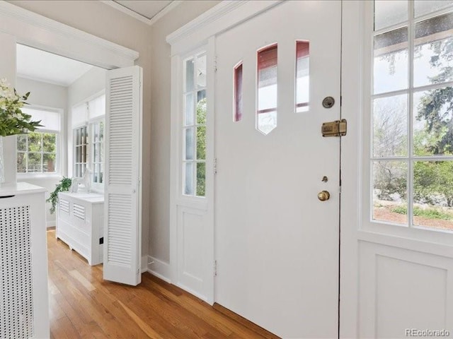 foyer entrance featuring light wood-type flooring, baseboards, and ornamental molding