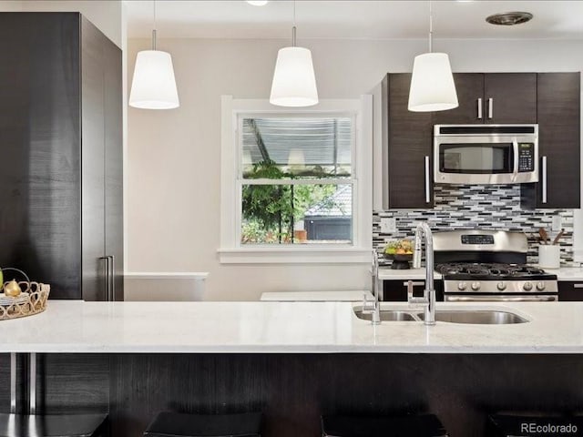 kitchen featuring appliances with stainless steel finishes, a breakfast bar area, dark brown cabinetry, and pendant lighting