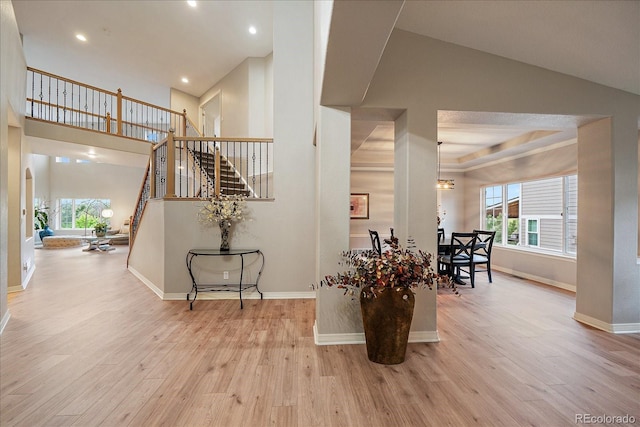 staircase with wood finished floors, baseboards, recessed lighting, and a towering ceiling