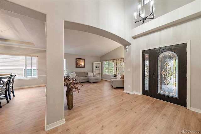 entrance foyer with wood finished floors, arched walkways, and baseboards